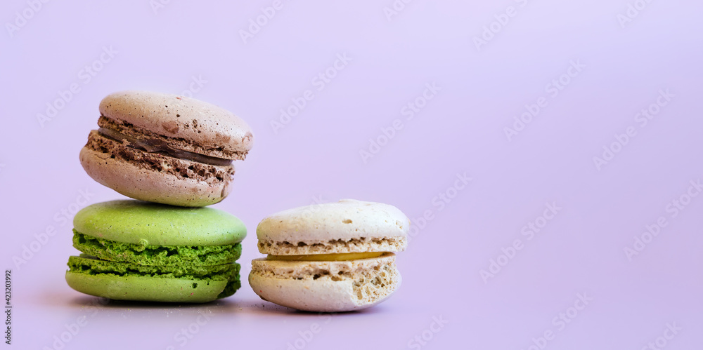 French macaroon cakes on a purple background with space for text French macaroon cakes on a purple background with space for text