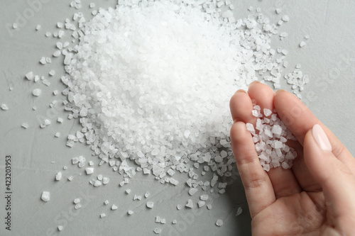 Foto Woman with natural sea salt at grey table, top view