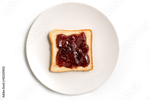 Slice of toasted bread with red strawberry jam in a white plate isolated on white background - top view