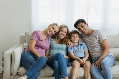 Happy family Caucasian parents hugging a child on the sofa at home.