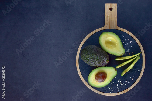 Appetizing cut avocado, sprinkled with coarse salt, on a black background