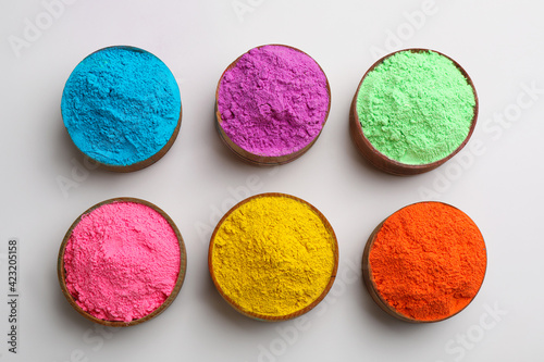 Colorful powders in bowls on light background, flat lay. Holi festival celebration