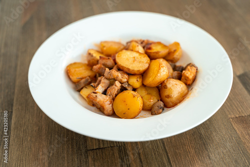 Potatoes with meat and mushrooms on a white plate