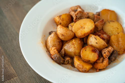 Potatoes with meat and mushrooms on a white plate