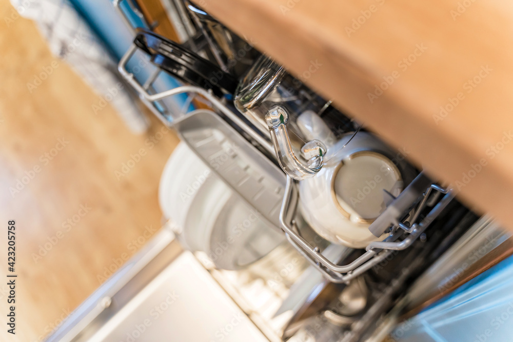 Obraz premium Clean dishes in the open dishwasher in the kitchen with light blue facades