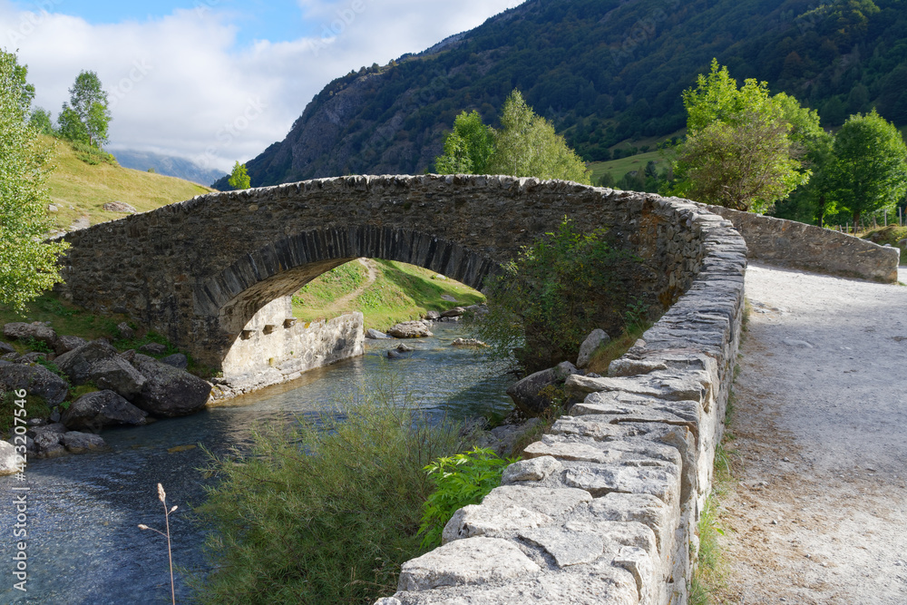 small stone bridge over a stream in front of the Pyrenees mountains in Gavarnie