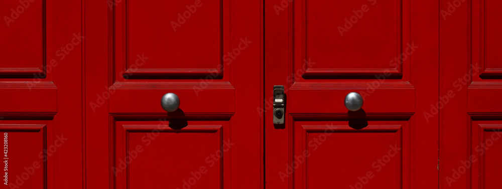 Portion of door in red lacquered wood with metal knobs and lock..