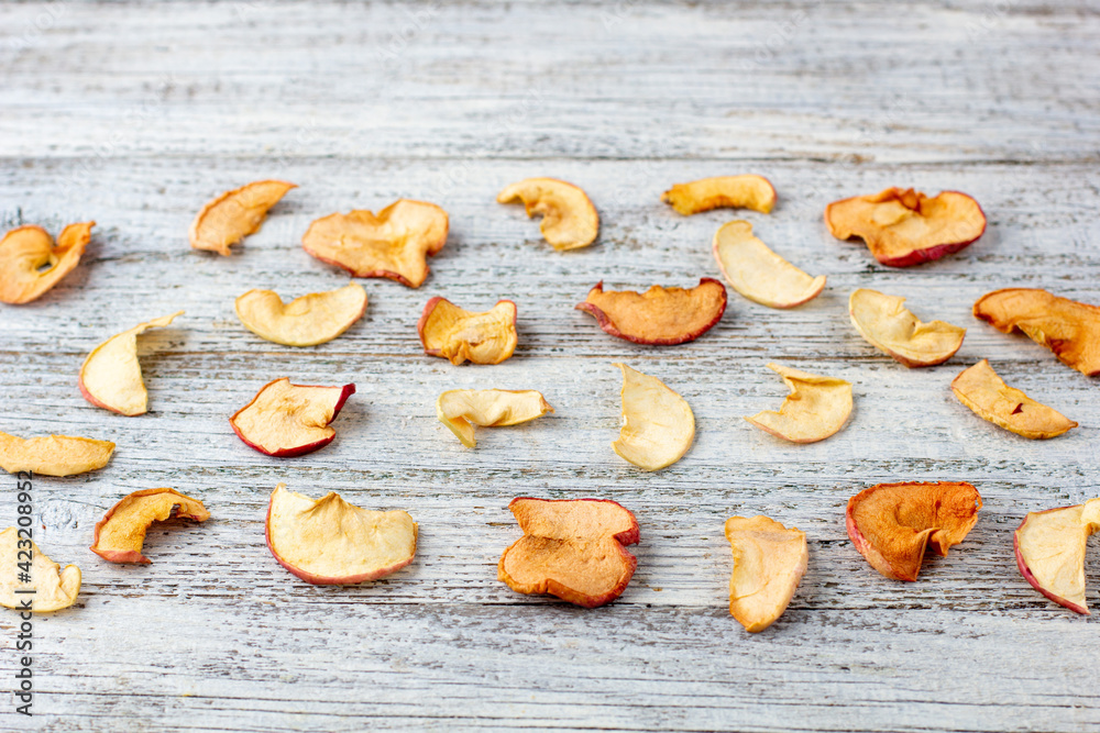 Pattern of a pile of dried apples in slices on a white wooden background. Dried fruit chips. Healthy food