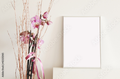 empty vertical picture frame with beautiful pink flowers on white wall background