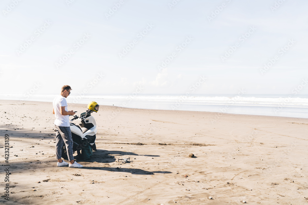 Male biker standing near bike and using remote control Male biker standing near bike and using remote control