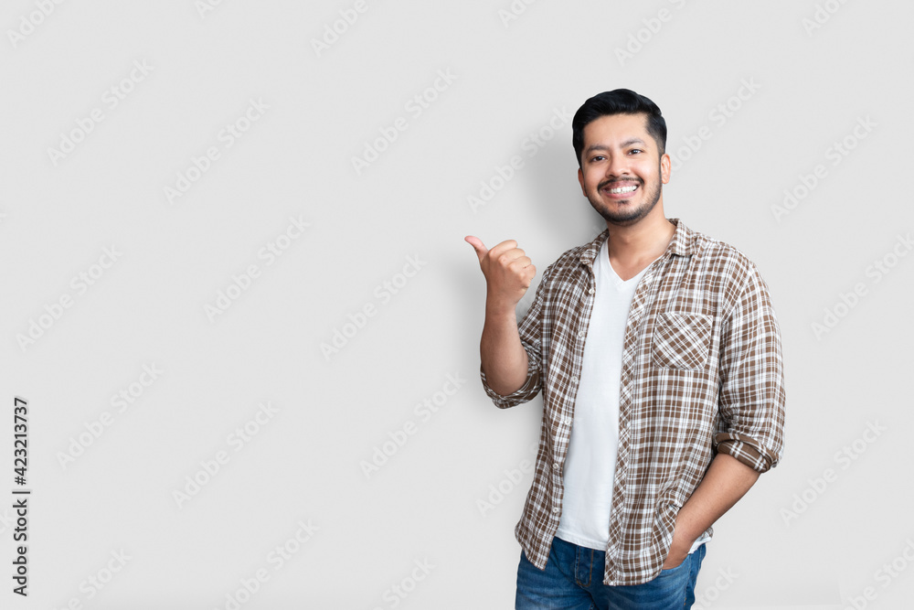 Adult asian man over isolated background smiling with happy face looking and pointing to the side with thumb up.