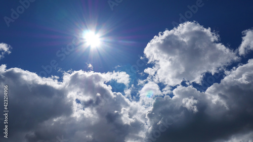 The sun is shining brightly against the blue sky and snow-white clouds. Summer