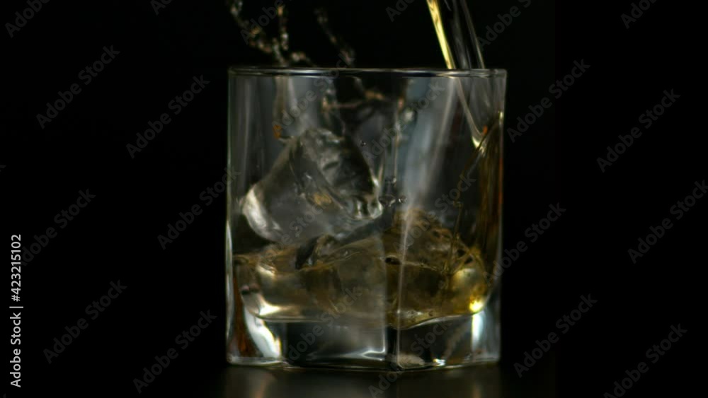 Slow Motion of Pouring Whiskey in Glass with Ice, Dark Background Slow Motion of Pouring Whiskey in Glass with Ice, Dark Background