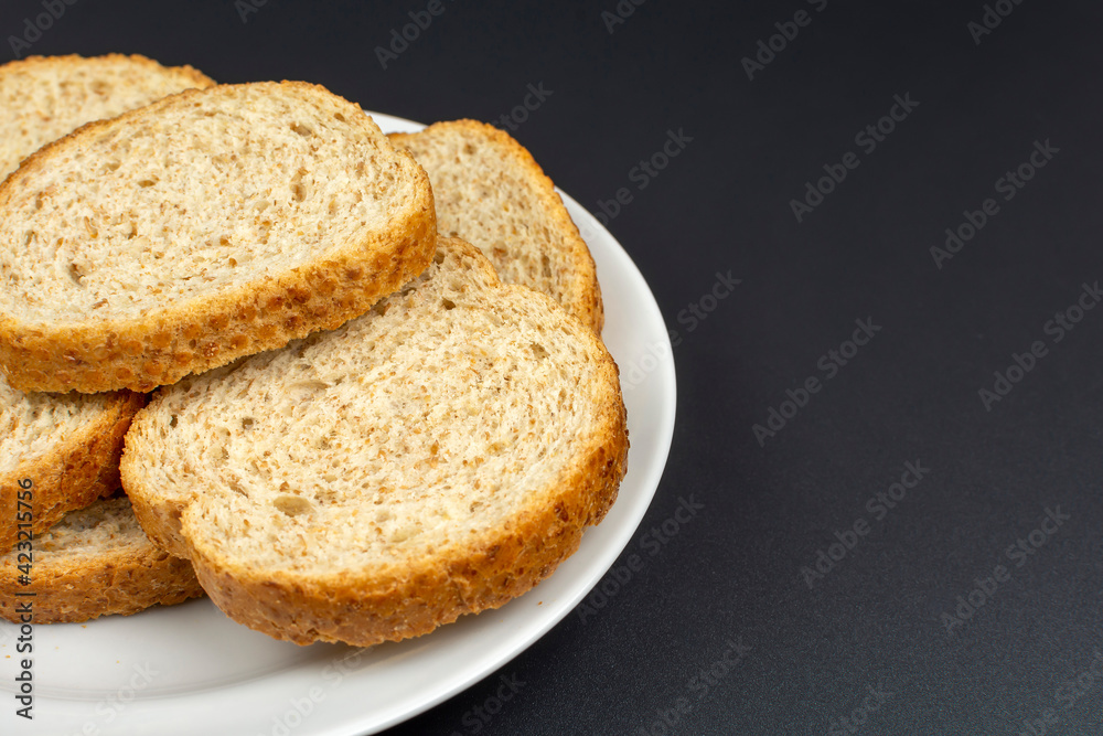 bread dried in the oven on a white ceramic plate on a black background