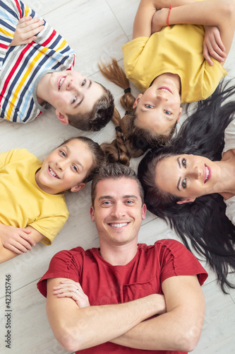Happy family lying on the floor smiles and looks up to the camera