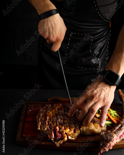 Chef cutting grilled T-bone steak before serving