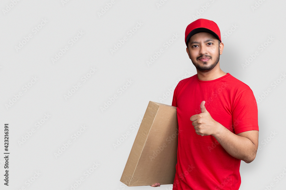 Delivery man employee in red cap blank t-shirt finger uniform hold empty cardboard box isolated on white background Delivery man employee in red cap blank t-shirt finger uniform hold empty cardboard box isolated on white background