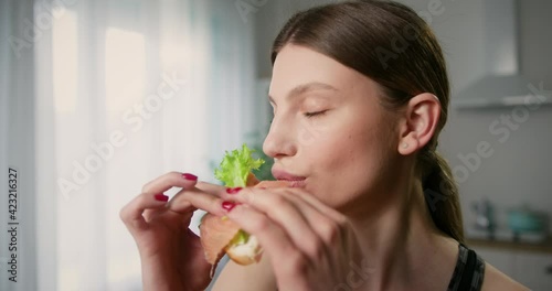 Zoom in shot of attractive young woman snacking on sandwich closing eyes from satisfaction. Healthy eating concept.