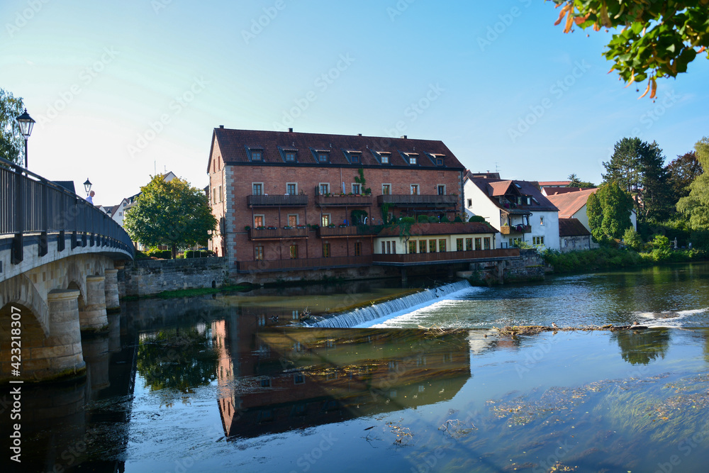 Obraz premium Staustufe der Pegnitz mit Jungmühlhof bei Lauf an der Pegnitz in Mittelfranken, Bayern, Deutschland im Sommer bei blauem Himmel