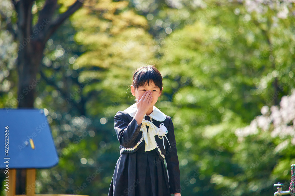 春の桜満開の公園で遊んでいる可愛い小学校一年生の子供の様子