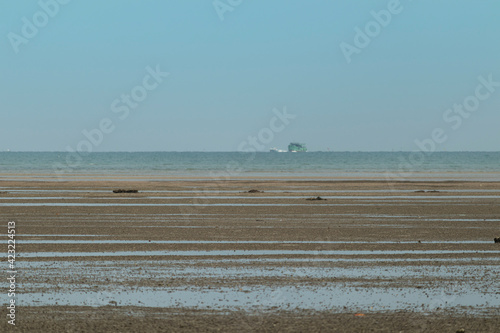 Sand floor on the beach after the sea has dropped. Become a wide beach with a background of a passenger ship