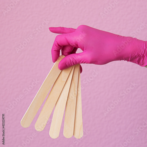 hands in pink gloves hold hair removal tools photo