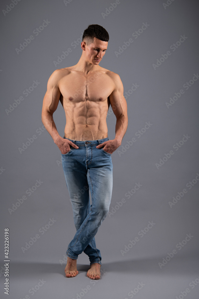 Shirtless guy with fit muscular torso and strong arms biceps triceps muscles pose in jeans, sport