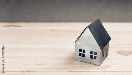 Miniature paper model of the house. Concept of mortgage, rent, purchase, protection, construction of a house. On a wooden background