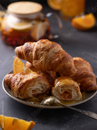 Beautiful food photo with breakfast: tea and croissants with orange jam. Food styling, black background.