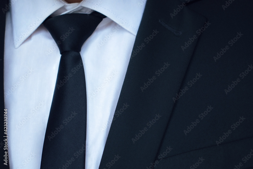 A business man in a black jacket, white shirt, and black tie. A business man in a black jacket, white shirt, and black tie.
