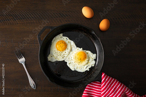 Overhead shot of fried eggs in a cast iron skillet. 