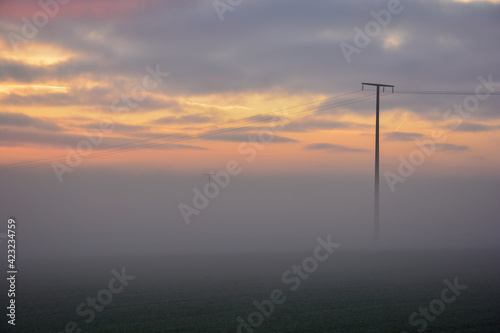 Strommast im Nebel im Sonnenuntergang bei Schweinfurt
