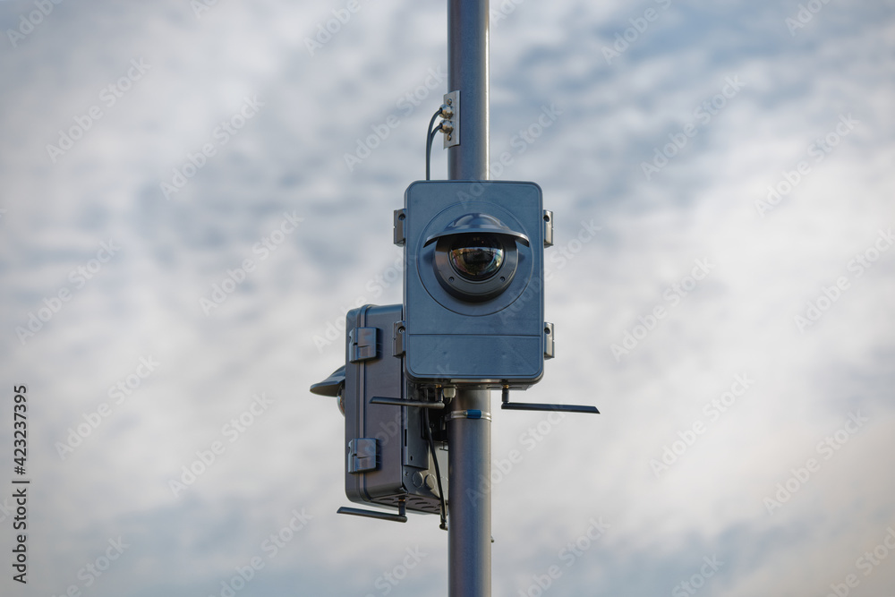 two large surveillance cameras on a light pole in cloudy sky with clouds in the background, dimmed light, during the day without people, two large surveillance cameras on a light pole in cloudy sky with clouds in the background, dimmed light, during the day without people,