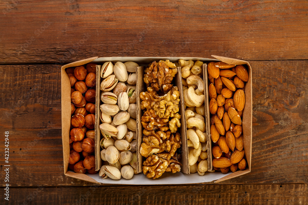 Assorted nuts in packaging on a brown wooden table.