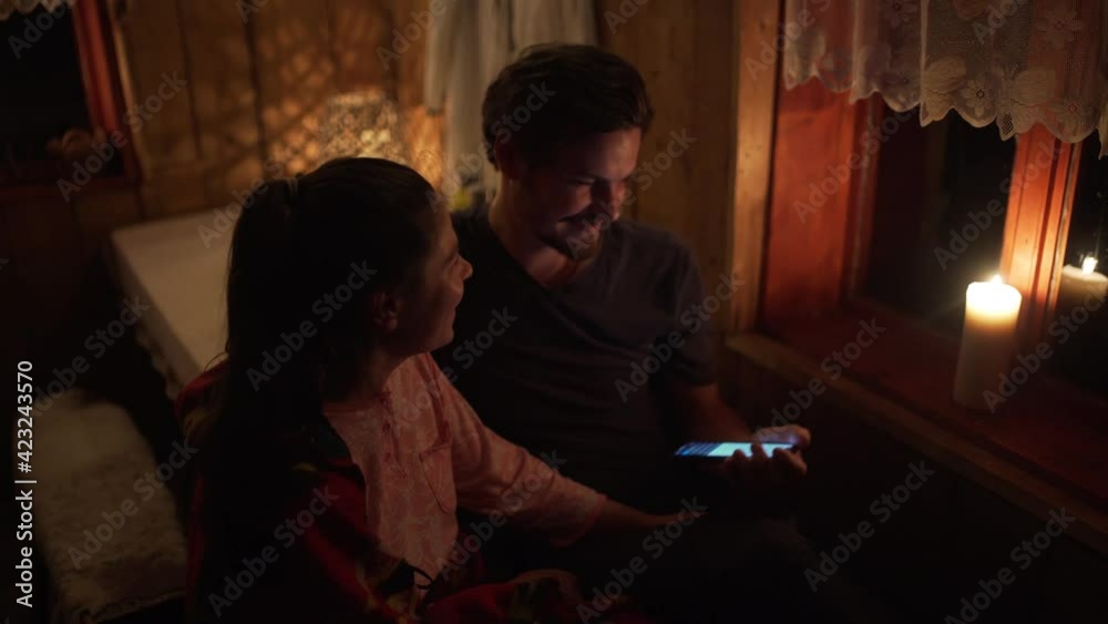 couple laughing and looking up something in the phone in the night in the candle light couple laughing and looking up something in the phone in the night in the candle light