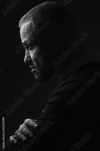 Fabulous at any age. Profile portrait of charismatic 40-year-old man standing over black background. Short haircut. Classic, smart casual style. Close up. Black and white studio shot