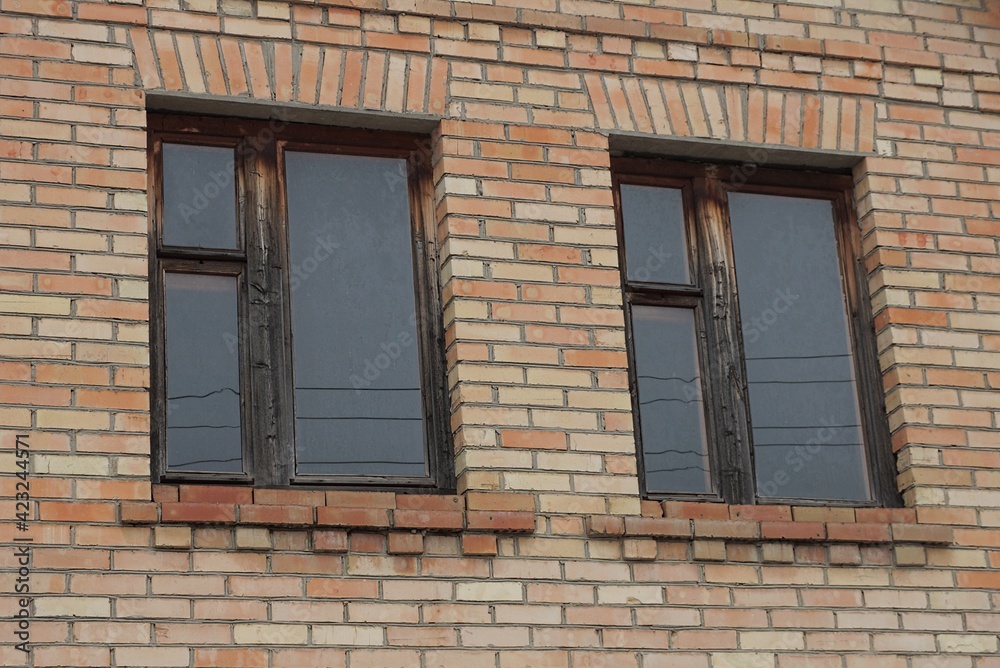 two old windows on a brown brick wall of a building