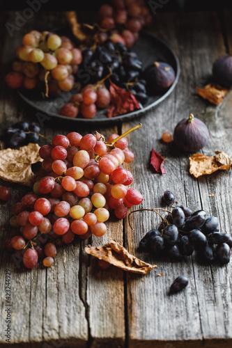 Grapes with dry leaves on a rustic background, autumn composition