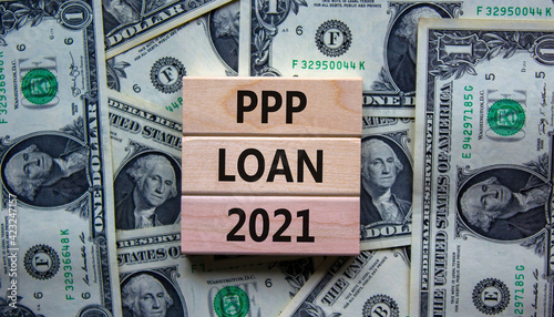 PPP, paycheck protection program loan 2021 symbol. Concept words PPP loan 2021 on blocks on a beautiful background from dollar bills. Business, PPP - paycheck protection program loan 2021 concept.