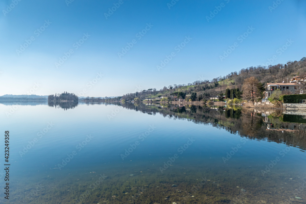 Houses and plants are reflected in the water of Lake Pusiano