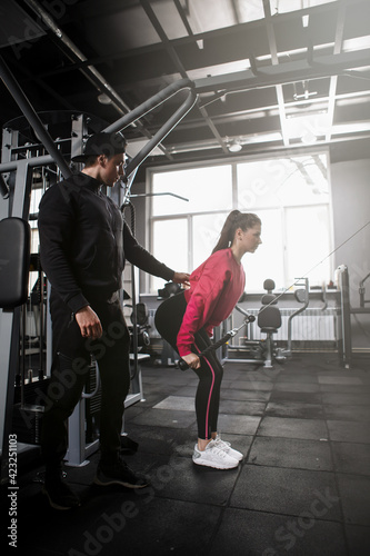 Vertical full length shot of a male personal trainer coaching his female client at the gym