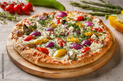 Vegetable Pizza on a wooden board with a beautiful vegetable background. Vegetarian.