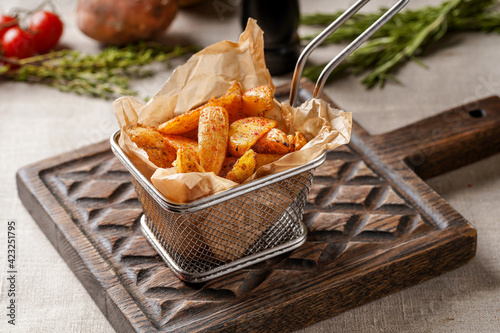 Rustic potatoes on a wooden chopping board with a beautiful background of vegetables and herbs.