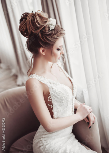 Beautiful bride in wedding dress in luxurious apartment. Fashion makeup and hairstyle. Portrait of young gorgeous bride. Wedding. Studio shot.