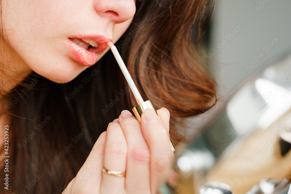 Young woman doing makeup, paints her lips with glitter Young woman doing makeup, paints her lips with glitter