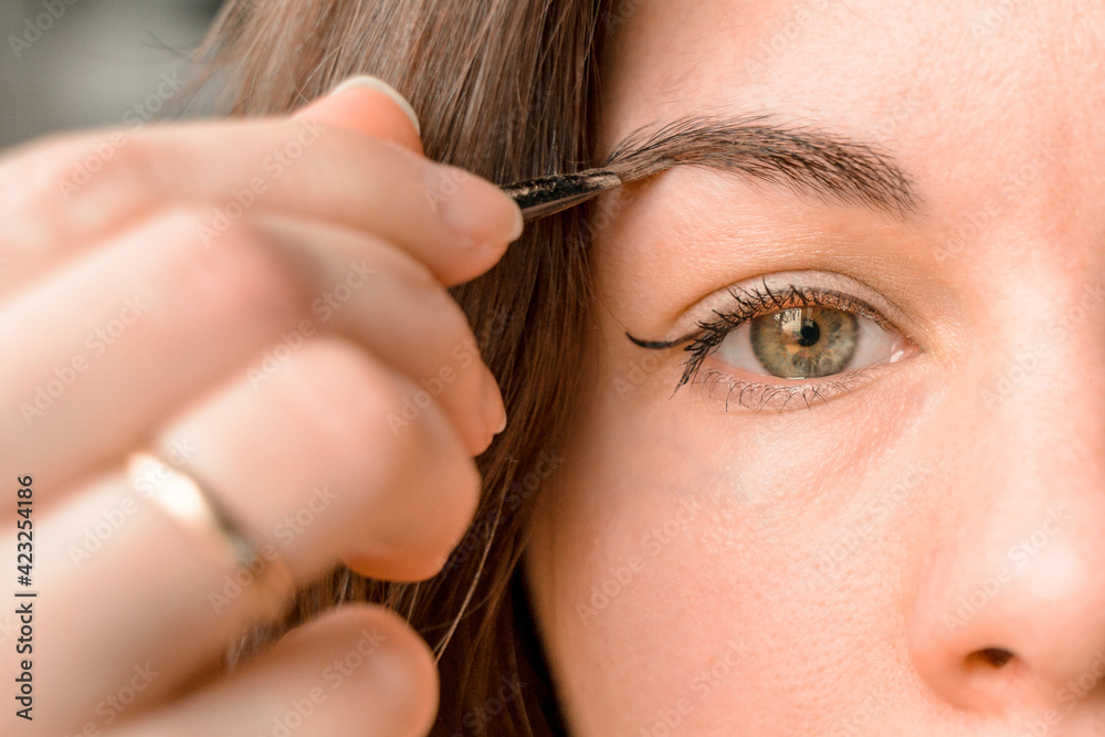 Obraz premium A young woman is doing makeup. The girl paints her eyes