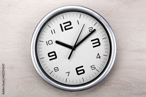 large white clock face with digits on a wooden background closeup