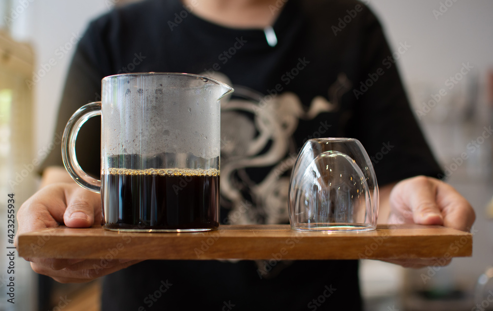 Drip coffee in a glass on a wooden tray ready to be served in a coffee shop.