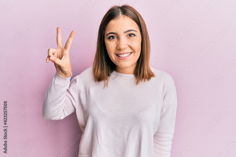 Young beautiful woman wearing casual clothes smiling with happy face winking at the camera doing victory sign. number two. Young beautiful woman wearing casual clothes smiling with happy face winking at the camera doing victory sign. number two.