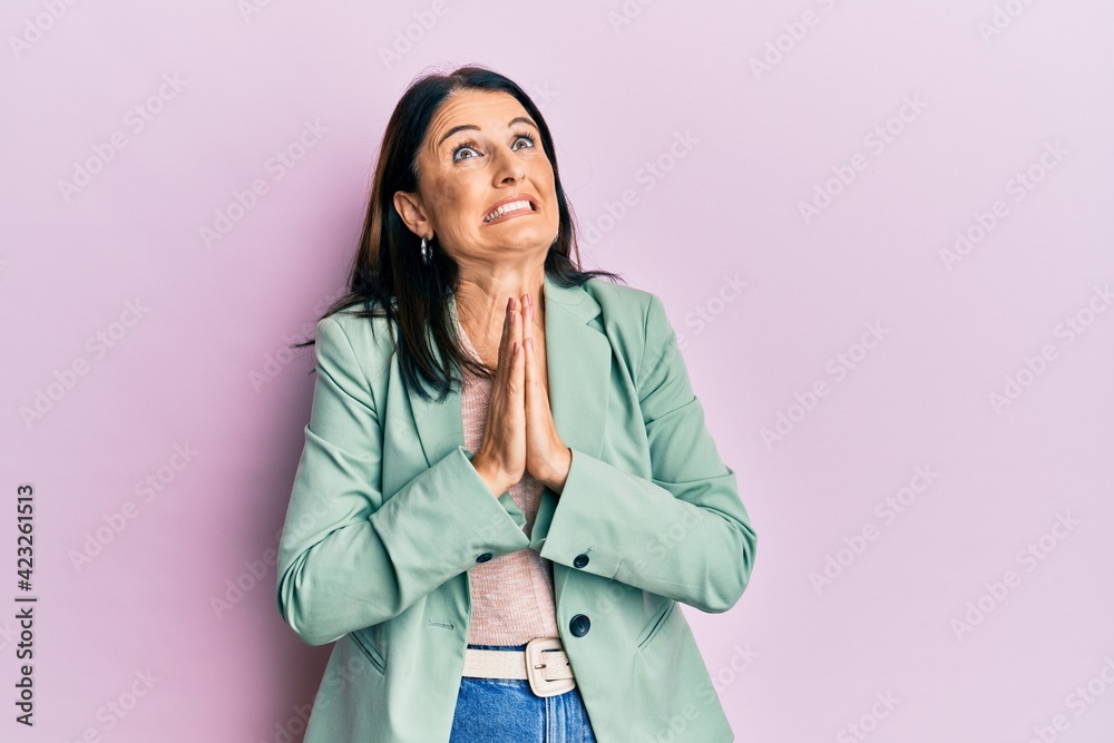 Middle age brunette woman wearing casual clothes begging and praying with hands together with hope expression on face very emotional and worried. begging.